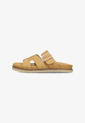 Sandalia tipo slip-on de ante color beige con dos tiras anchas, una hebilla plateada y suela de goma beige texturizada.