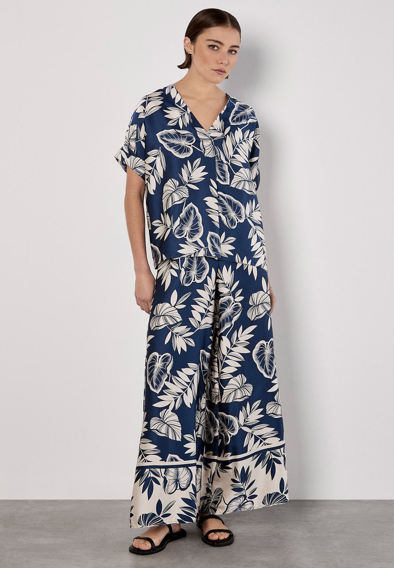 Completo floreale blu navy composto da una blusa a maniche corte e pantaloni a gamba larga, realizzati in tessuto morbido con dettagli crema e motivi a foglia.