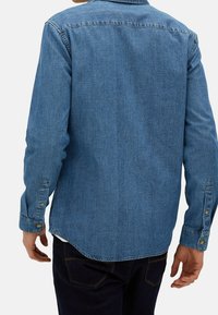 Denim shirt in medium blue, lange mouwen met knoopmanchetten, afgeronde zoom en een yoke-detail op de rug. Eenvoudig en klassiek ontwerp.
