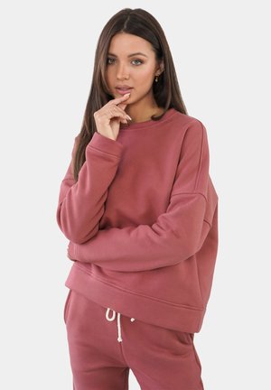 Übergröße, Sweatshirt mit Rundhalsausschnitt in staubigem Rosé, aus weichem Stoff mit gerippten Bündchen und Saum. Kombiniert mit passenden Jogginghosen.