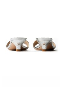Paire de mules argentées à talons ouverts, avec petits talons aiguilles bas et design texturé, vues de dos sur un fond blanc.