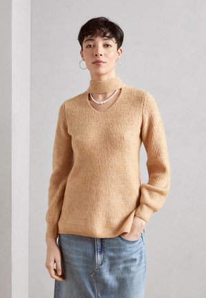 Pull en maille beige clair avec un col haut et un décolleté en V. Fabriqué en tissu doux, il présente des manches longues et une coupe décontractée.