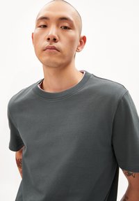 Donkergroene T-shirt met korte mouwen van katoen, met een ronde halslijn en een gladde textuur, voorzien van zichtbare stiksels op de schouders.