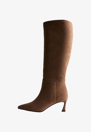 Stivale in pelle scamosciata marrone al ginocchio con punta affilata e tacco medio. Texture liscia, design aderente e dettagli di cucitura minimi.
