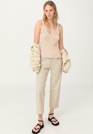 Canotte a coste beige, pantaloni crema e sandali neri. La canotta presenta un design a scollo a V e i pantaloni hanno una vestibilità cropped.