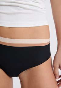 Czarne bikini z gładką teksturą, z warstwowym elastycznym pasem w odcieniach beżu. Zbliżenie ukazujące dopasowanie i wzór.