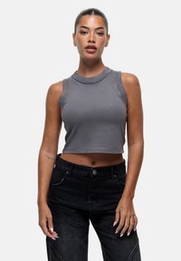 Grijze cropped tanktop met een ronde hals, mouwloos ontwerp, gladde textuur, gecombineerd met high-waisted zwarte jeans met voorkleding.