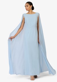 Robe longue bleu clair avec une cape, présentant un encolure bateau et une silhouette épurée. Fabriquée en tissu doux avec une texture lisse.