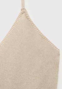 Beige knitted bralette with a triangular shape, featuring thin straps and a textured knit pattern.