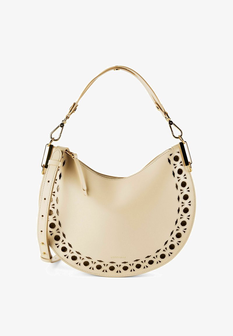 Beige crescent-shaped leather handbag with floral cutout patterns along edges, gold hardware, a top handle, and an adjustable shoulder strap.