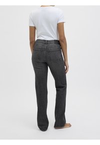 Grå raka jeans med hög midja, försedda med två bakfickor och en subtil blekt textur, i kombination med en vit t-shirt med kort ärm.