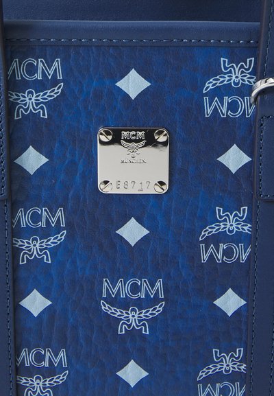 Sac MCM bleu avec logo en relief et motif en diamant. Présente une plaque logo en argent, une texture lisse et des détails de couture renforcée.