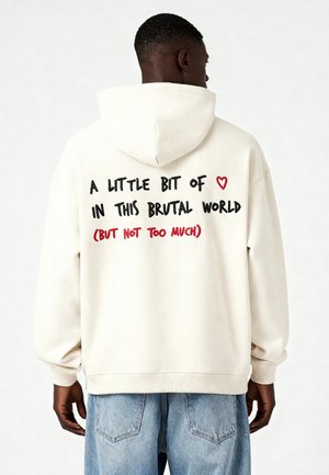 Crème katoenen hoodie met een trekkoord in de capuchon. Aan de achterkant staat grafische tekst in zwart en rood met de tekst "EEN BEETJE ❤️ IN DEZE BRUTALE WERELD (MAAR NIET TE VEEL)."