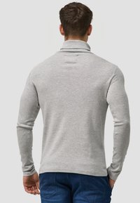 Szara, długosleeve polo z wysokim kołnierzem, dopasowany krój i gładka faktura materiału, w połączeniu z niebieskimi dżinsami.