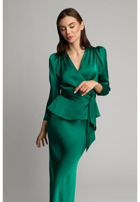 Sukienka z satyny w kolorze szmaragdowej zieleni, z długimi bufiastymi rękawami, peplum w talii oraz kokardą, o gładkiej, błyszczącej fakturze.