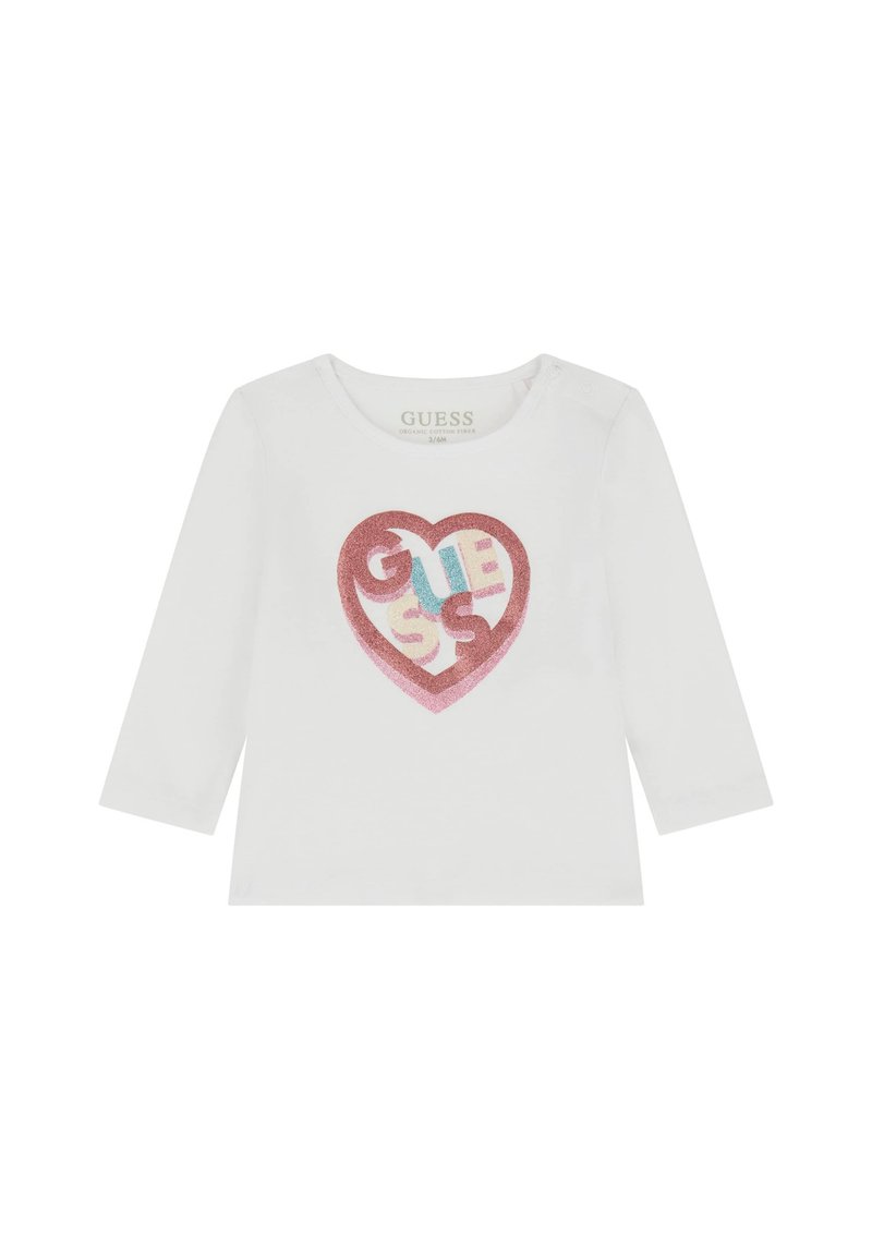 Maglietta bianca a maniche lunghe con un grafico di un cuore di glitter rosa che presenta il testo "GUESS" in blu, giallo e rosso. Realizzata in cotone biologico.