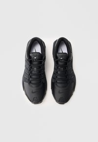 Sapatos atléticos pretos com um design texturizado, fecho com atacadores e um superior sintético liso. Apresenta um logótipo proeminente de lado.