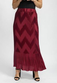 Plisseret maxiskørt i bordeaux med et zigzag-mønster. Har en elastisk talje og et let, tekstureret stof. Sorte sandaler komplementerer.