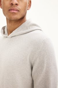 Hellgrauer Hoodie aus weichem Stoff, mit rundem Ausschnitt und Kapuze sowie glatter Textur. Nahaufnahme des Oberkörpers.