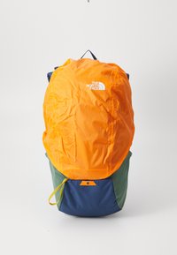 Mochila con una parte superior de color naranja brillante, base azul y acentos verdes. Hecha de un tejido duradero, cuenta con un logo y un asa en la parte superior para llevarla.