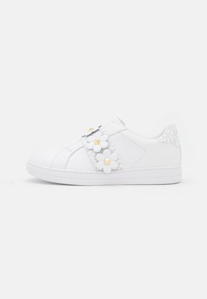 White sneaker with floral strap featuring three white flowers with gold square studs and patterned heel accent.