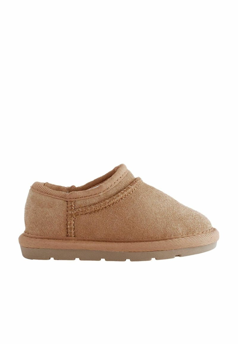 Barna slip-on cipők, puha szövetből, lekerekített orral és texturált felülettel. Alacsony gumitalp és varrott részletek láthatók.