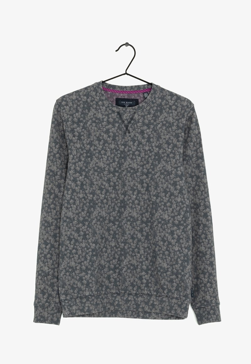 Sweat-shirt gris à manches longues avec un motif floral subtil, col rond et détail violet à l'intérieur du col, suspendu à un cintre noir.