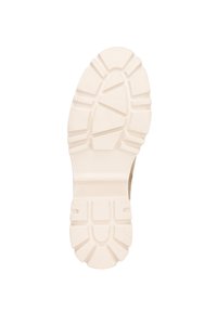 Suela de un zapato con un diseño texturizado y estriado en color crema. Presenta surcos profundos para agarre y estabilidad.