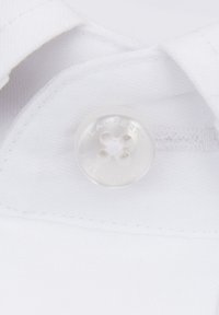 Przezroczysty plastikowy guzik z czterema otworami, przymocowany do białej tkaniny odzieżowej. Widoczne szycie wokół obszaru guzika, gładka tekstura.