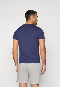 Jūras spēku zila īsām piedurknēm T-kreklu, izgatavots no mīksta auduma, ar klasisku apaļu kakla izgriezumu. Apvienots ar pelēkiem šortiem, ar brīvu piegriezumu.