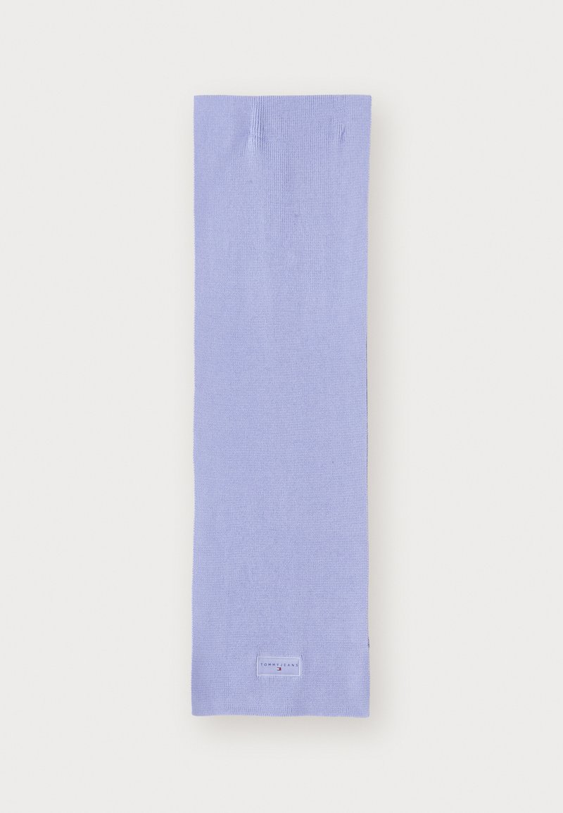 Calcetín de color lila, hecho de una tela suave, con una textura lisa. Presenta una pequeña etiqueta rectangular con logo en el tobillo.