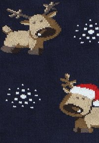Dzianina ma ciemnogranatowe tło z kreskówkowymi reniferami w jasnobrązowym kolorze, z jednym noszącym czerwony czapkę Mikołaja, ozdobionym białymi płatkami śniegu.