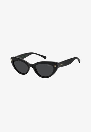 Lunettes de soleil noires forme œil de chat avec verres foncés, accents de points dorés près des charnières et logo Polaroid sur la branche.