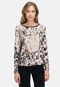Leopardprint lange mouw top met een crèmekleurige basis, zwarte halslijn en een versierde graphic met de woorden "Glitter" en "Sparkle."