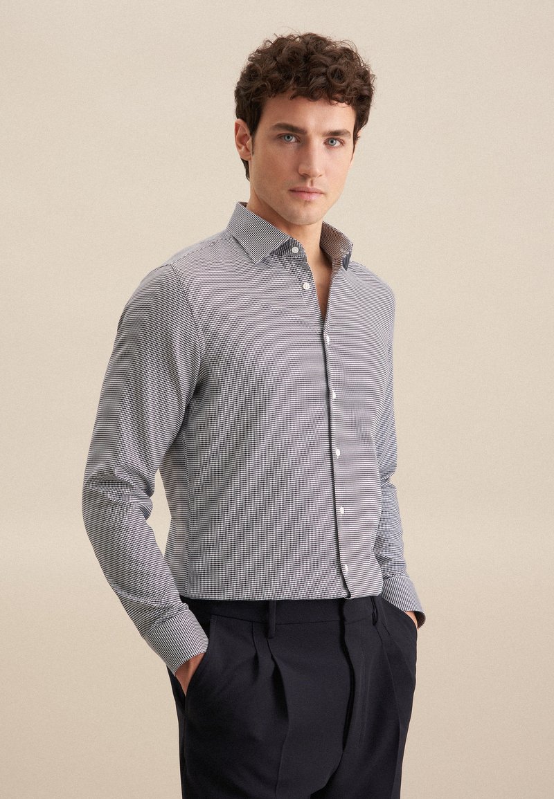 Camicia button-up in un motivo a quadri blu e bianco, con maniche lunghe, colletto a punta e design aderente. Il tessuto è liscio con una leggera consistenza.