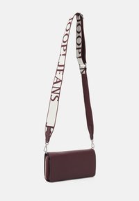 Bordeaux crossbody taske med tekstureret læder, lynlåslukning og justerbar rem med logo print i crème. Slank rektangulær form.