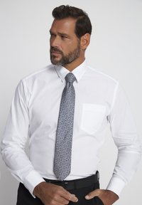 Chemise blanche à col, avec une poche poitrine simple et des manches longues, accompagnée d'une cravate bleue à motifs avec des dessins floraux.