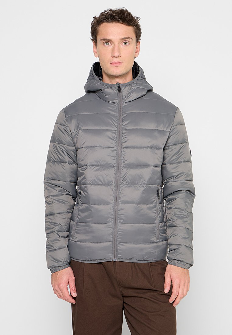 Chaqueta de plumas gris con capucha, que presenta un cierre de cremallera, costuras horizontales y bolsillos laterales. Ligera, de textura suave.