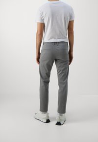 Grå skräddarsydda byxor med ett strukturerat mönster, slim fit-design, två bakfickor, i kombination med vita sneakers och vita strumpor.