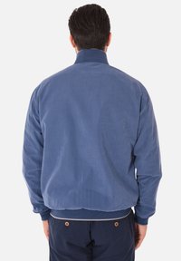 Giacca bomber in cotone blu con una consistenza morbida, collo e polsini a coste e una vestibilità rilassata. Nessun motivo o accento visibile.