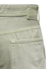 Light green cotton pants featuring a rear pocket, stitched details, and a smooth texture. The waistband has an elastic finish for comfort.