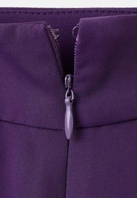 Tissu violet avec une texture lisse présentant une fermeture éclair centrée en haut, mettant en valeur son design fonctionnel et sa cohérence de couleur.