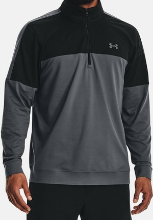Mann trägt einen langärmeligen, zweifarbigen schwarzen und grauen Athletic-Pullover mit Viertelreißverschluss und Under Armour-Logo auf der Brust.