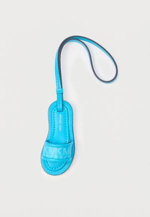 Blauwe leren Michael Kors sleutelhanger in de vorm van een sandaal met polsbandje op een witte achtergrond.
