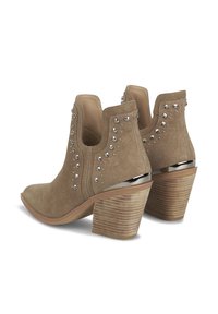 Zamszowe botki za kostkę w jasnobrązowym kolorze ze srebrnymi ćwiekami i błyszczącym srebrnym akcentem na obcasie. Projekt z blokowym obcasem o fakturowanym wyglądzie przypominającym drewno.