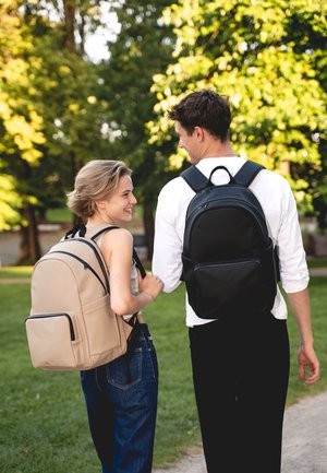 Két hátizsák látható: az egyik bézs színű, elülső zsebbel és cipzárral, a másik fekete, sima felülettel rendelkezik. Mindkettő állítható vállpántokkal van ellátva.