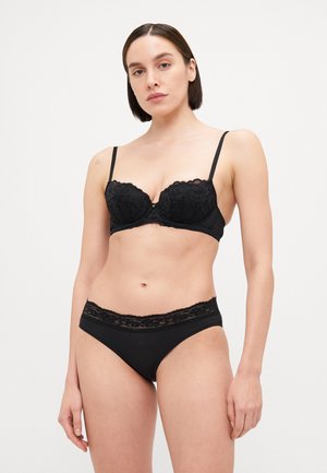 Reggiseno in pizzo nero con coppe imbottite e spalline regolabili, abbinato a mutandine nere coordinate con un bordo in pizzo sulla vita.