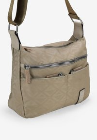 Bolso cruzado beige con un acabado texturizado, que cuenta con una solapa y bolsillos con cremallera. Correa ajustable y detalle del logo en la esquina inferior.