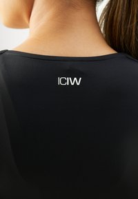 Zwarte sporttop met een ronde halslijn en een gladde textuur, voorzien van een prominent wit "ICIW" logo op de bovenrug.