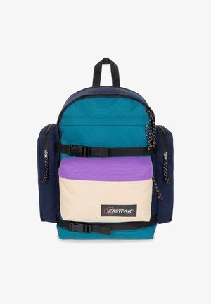Zaino Eastpak multicolore con una combinazione di tessuti blu navy, teal, beige e viola, dotato di numerose tasche con zip e spallacci regolabili.